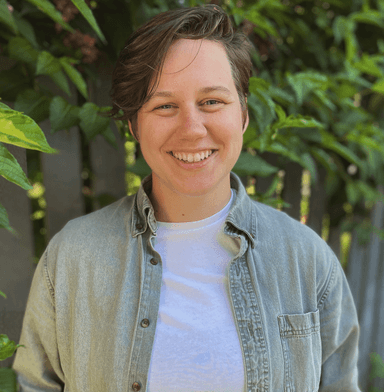 Hal standing in front of a leafy green bush, facing the camera, smiling.